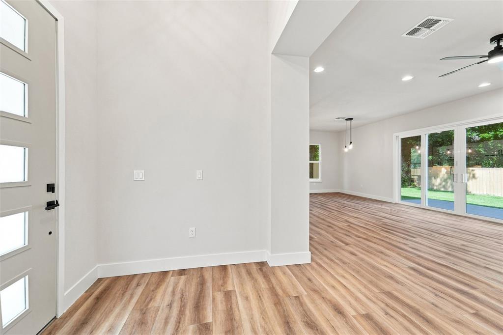 An entryway with light wood-look flooring leads into an open living area with sliding doors — 561 N THOMPSON ROAD, APOPKA, FL