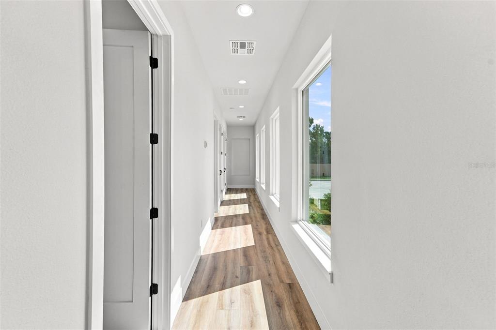 A bright hallway features white walls, wood-look flooring, recessed lighting, and large windows — 561 N THOMPSON ROAD, APOPKA, FL