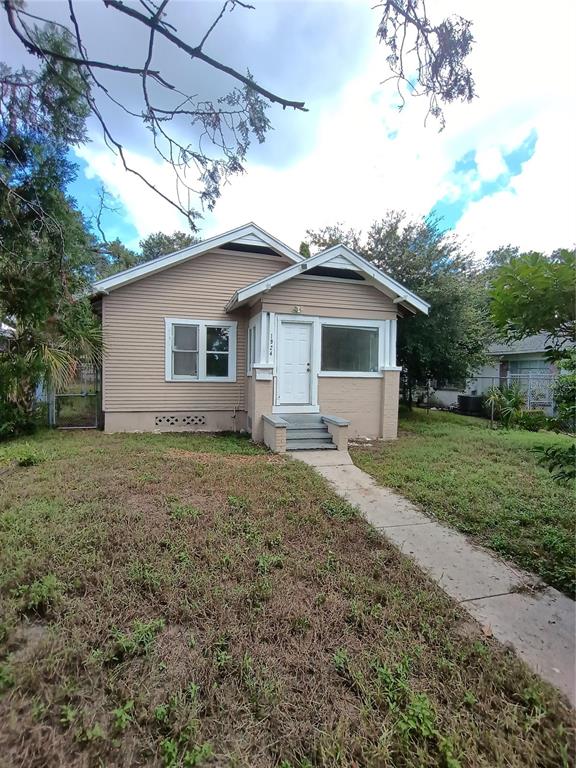 The exterior side of a house features beige siding, a chimney, and an air conditioning unit — 1924 30TH STREET S, ST PETERSBURG, FL
