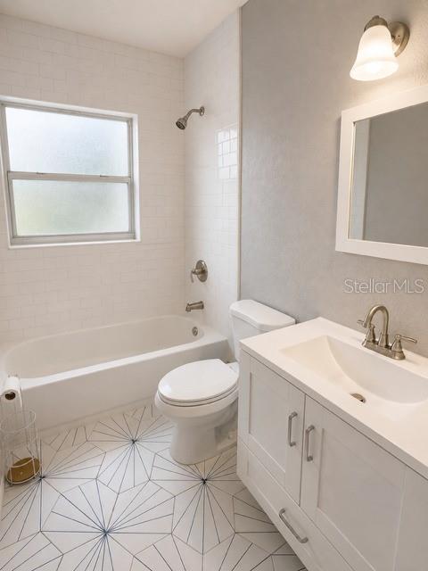 A bathroom features a white bathtub, a toilet, and patterned geometric floor tiles — 4307 W MAIN STREET, TAMPA, FL