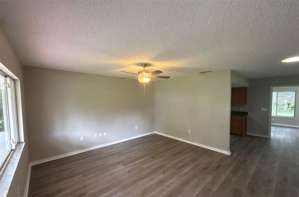 An empty living room with light gray walls, wood-look flooring, and a ceiling fan — 17655 SE 102ND CIRCLE, SUMMERFIELD, FL