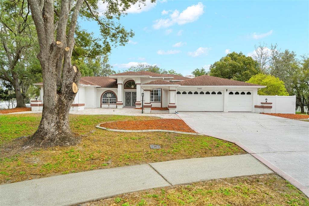A single-story house with a white exterior, brown roof, and a three-car garage — 348 FLORIAN WAY, SPRING HILL, FL