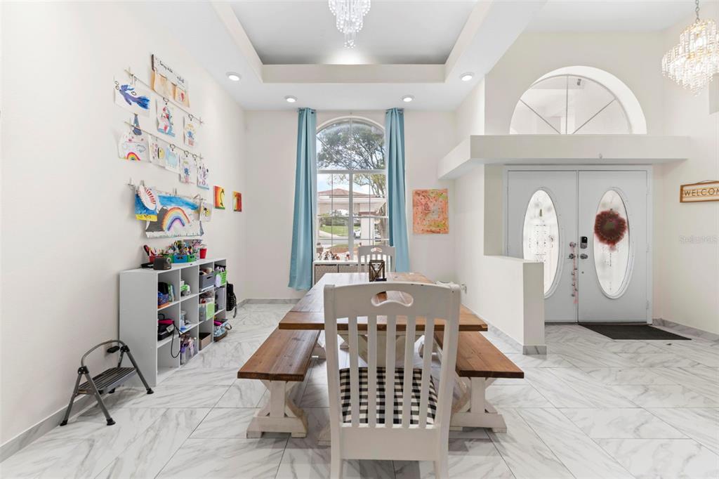 A dining room with a wooden table, benches, white tile floors, and a large window — 348 FLORIAN WAY, SPRING HILL, FL