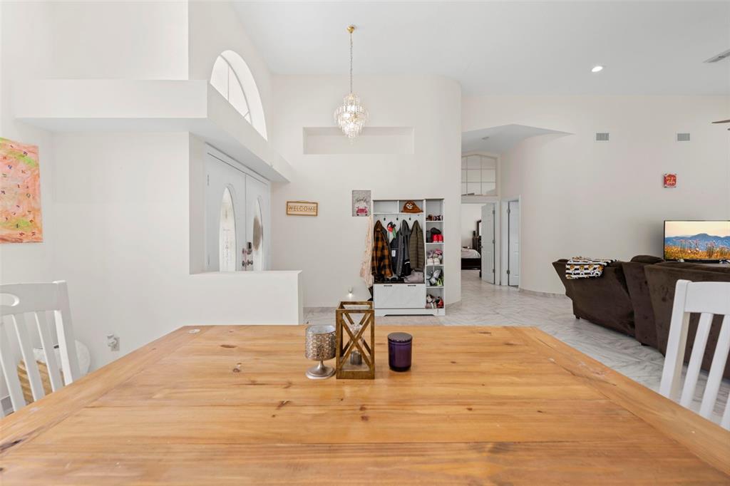 A dining room with a wooden table, white chairs, and a view into the living area — 348 FLORIAN WAY, SPRING HILL, FL