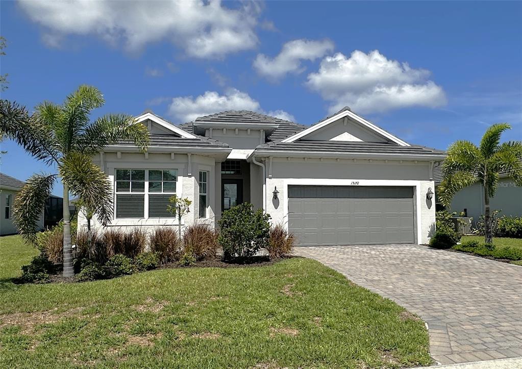 A single-story house with a gray garage, light-colored stucco exterior, and palm trees in front — 15172 RIVER BIRCH COURT, PUNTA GORDA, FL