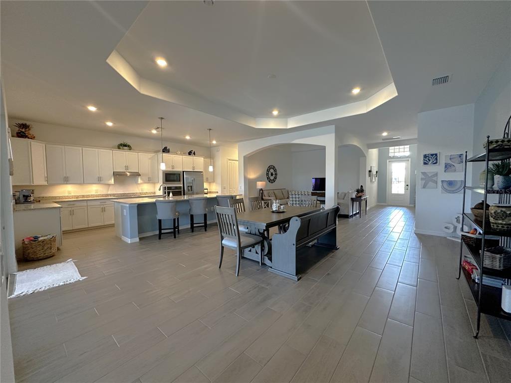 An open-concept kitchen and dining area features white cabinetry, a large island, and tile flooring — 15172 RIVER BIRCH COURT, PUNTA GORDA, FL