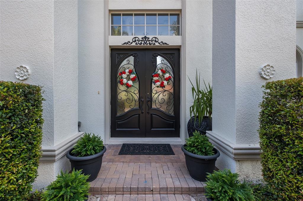 A double front door with glass inserts and wreaths is framed by white pillars — 10628 PONTOFINO CIRCLE, TRINITY, FL