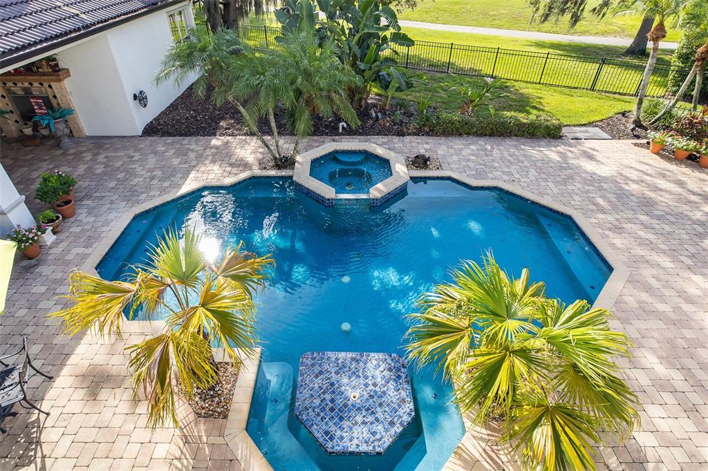 An aerial view of a backyard swimming pool with a spa and surrounding paver patio — 10628 PONTOFINO CIRCLE, TRINITY, FL
