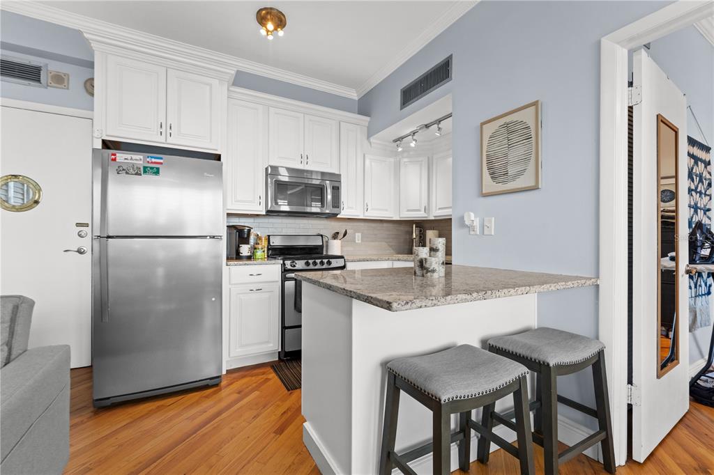 A kitchen features white cabinets, stainless steel appliances, a granite-topped island, and two bar stools — 2109 BAYSHORE BOULEVARD UNIT 303, TAMPA, FL