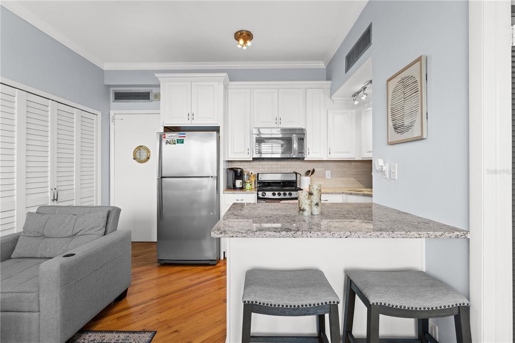 A kitchen with white cabinets, stainless steel appliances, and a granite-topped breakfast bar — 2109 BAYSHORE BOULEVARD UNIT 303, TAMPA, FL