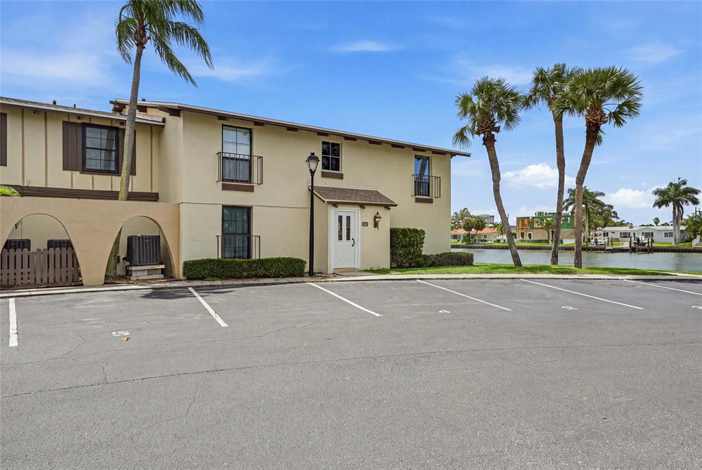 A two-story tan building with a parking lot and waterfront view — 501 PLAZA SEVILLE COURT UNIT 2, TREASURE ISLAND, FL