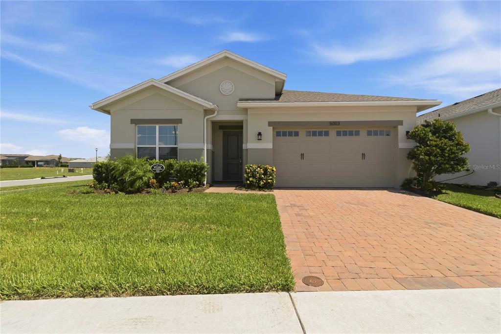 A single-story house with a beige exterior, a brick paver driveway, and a two-car garage — 5003 DANCY LANE, ST CLOUD, FL