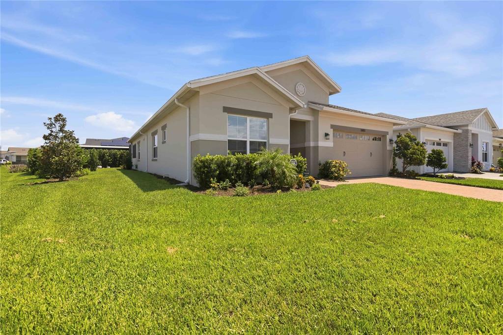 A single-story suburban house with a tan exterior, a two-car garage, and a grassy lawn — 5003 DANCY LANE, ST CLOUD, FL