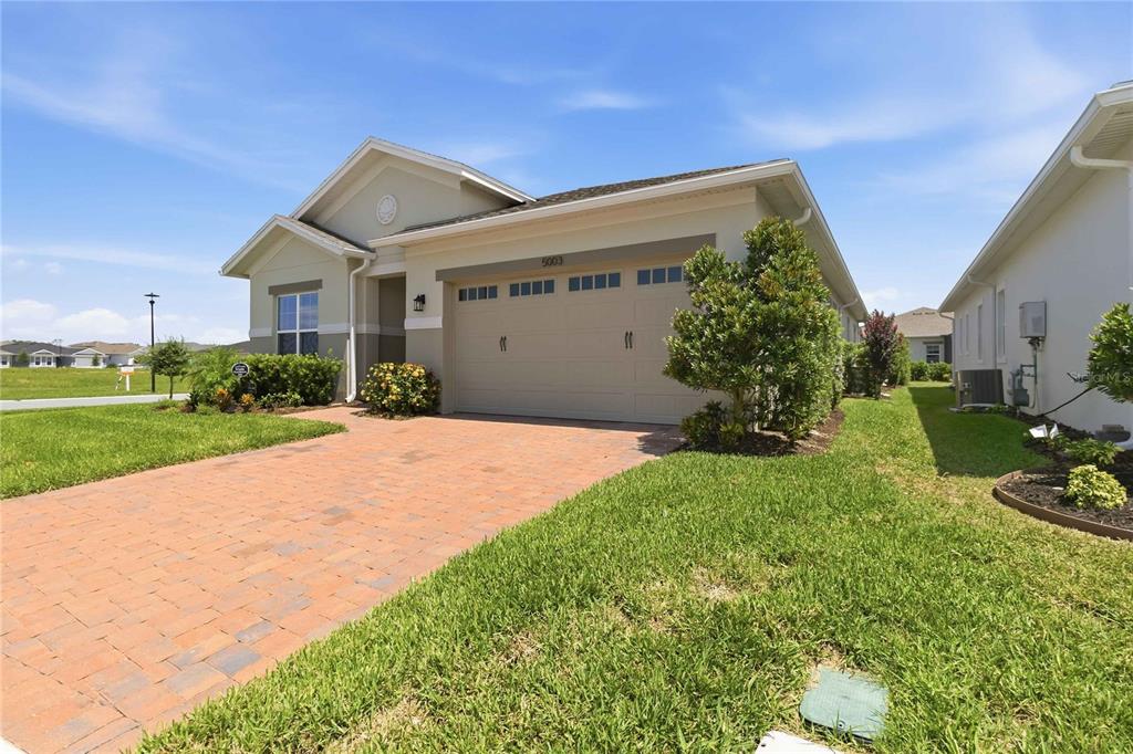 A single-story house with a beige exterior, a two-car garage, and a brick paver driveway — 5003 DANCY LANE, ST CLOUD, FL