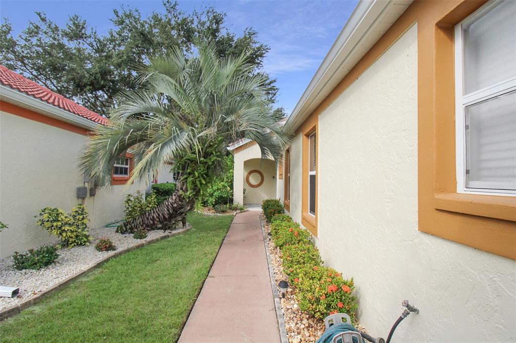 A concrete walkway leads toward a covered entryway between two light-colored stucco houses — 1304 CAPRI ISLES BOULEVARD UNIT 31, VENICE, FL