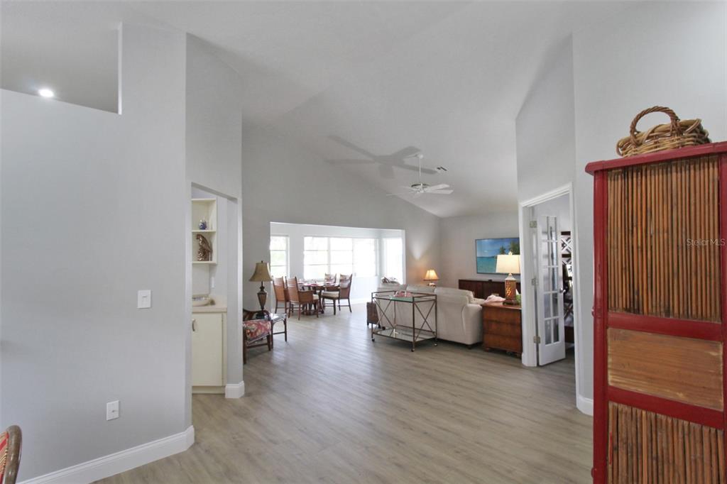 A spacious living and dining area with vaulted ceilings, light wood flooring, and neutral walls — 1304 CAPRI ISLES BOULEVARD UNIT 31, VENICE, FL