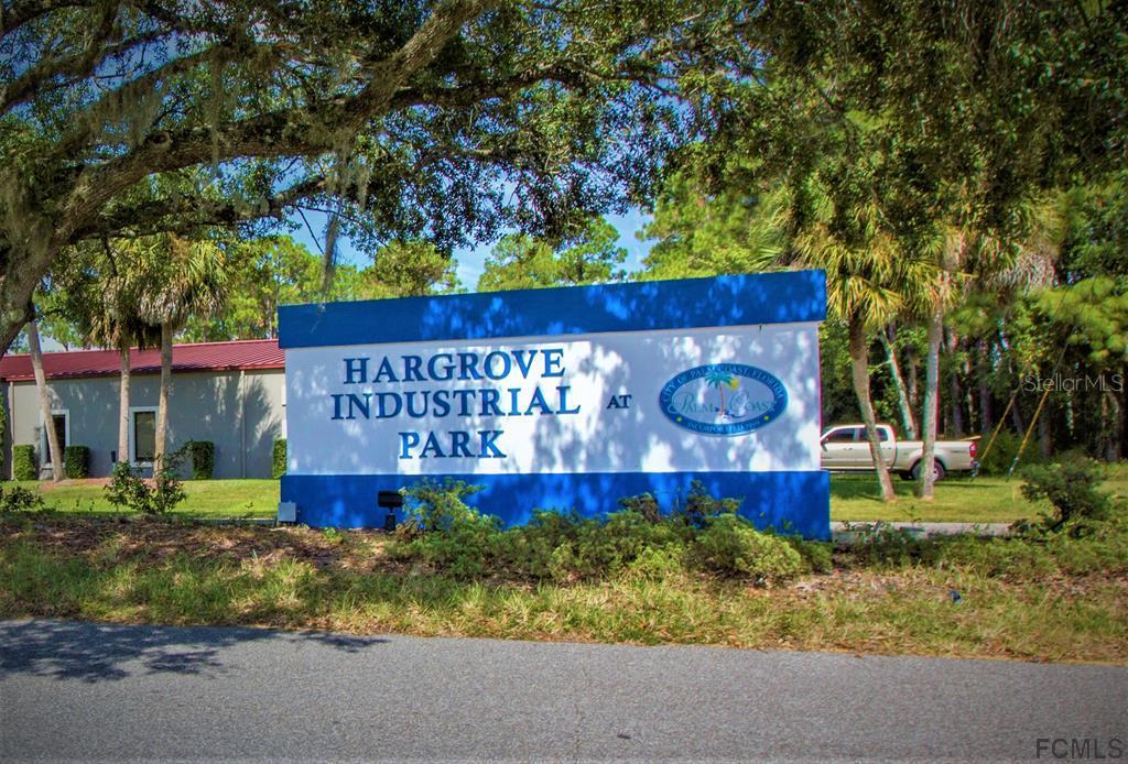 A blue and white sign for Hargrove Industrial Park stands in a grassy, tree-lined area — 26 HARGROVE GRADE UNIT 1, PALM COAST, FL