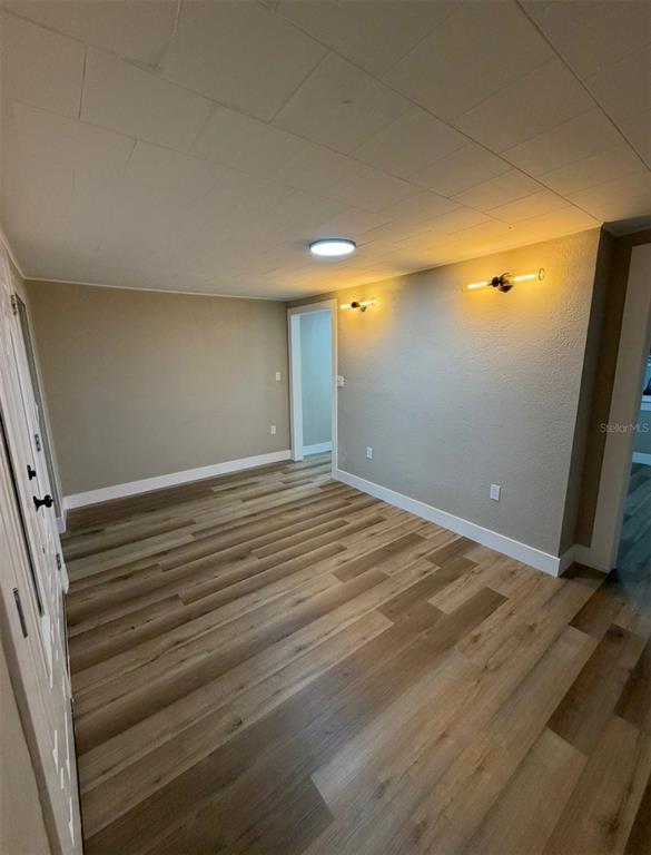 An empty room features light wood-look flooring, beige walls, and two wall-mounted light fixtures — 1221 E DR MARTIN LUTHER KING JR BOULEVARD, TAMPA, FL