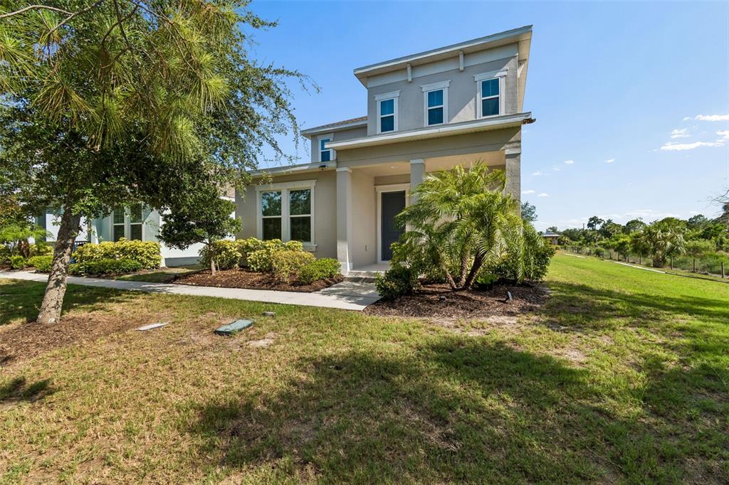 A two-story house with a beige exterior, a front porch, and a landscaped yard — 803 WINTERSIDE DRIVE, APOLLO BEACH, FL