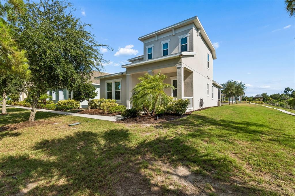 A two-story house with a covered front porch stands on a grassy lot with trees — 803 WINTERSIDE DRIVE, APOLLO BEACH, FL