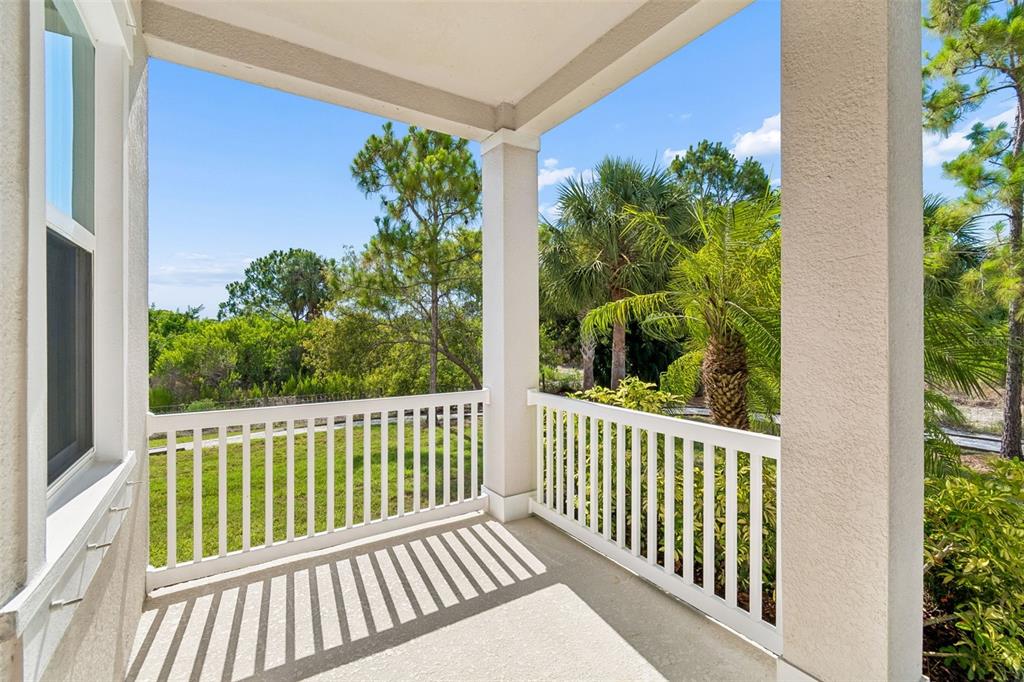 A covered balcony with white railings overlooks a grassy yard and surrounding trees — 803 WINTERSIDE DRIVE, APOLLO BEACH, FL