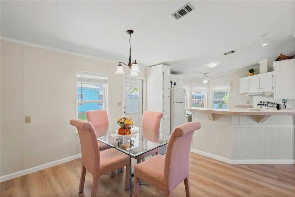 A dining area with a glass table and pink chairs sits beside an open kitchen — 693 RIVERVIEW CIRCLE, NORTH PORT, FL
