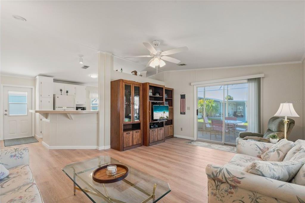 A living room with light wood flooring, a ceiling fan, and an open kitchen area — 693 RIVERVIEW CIRCLE, NORTH PORT, FL