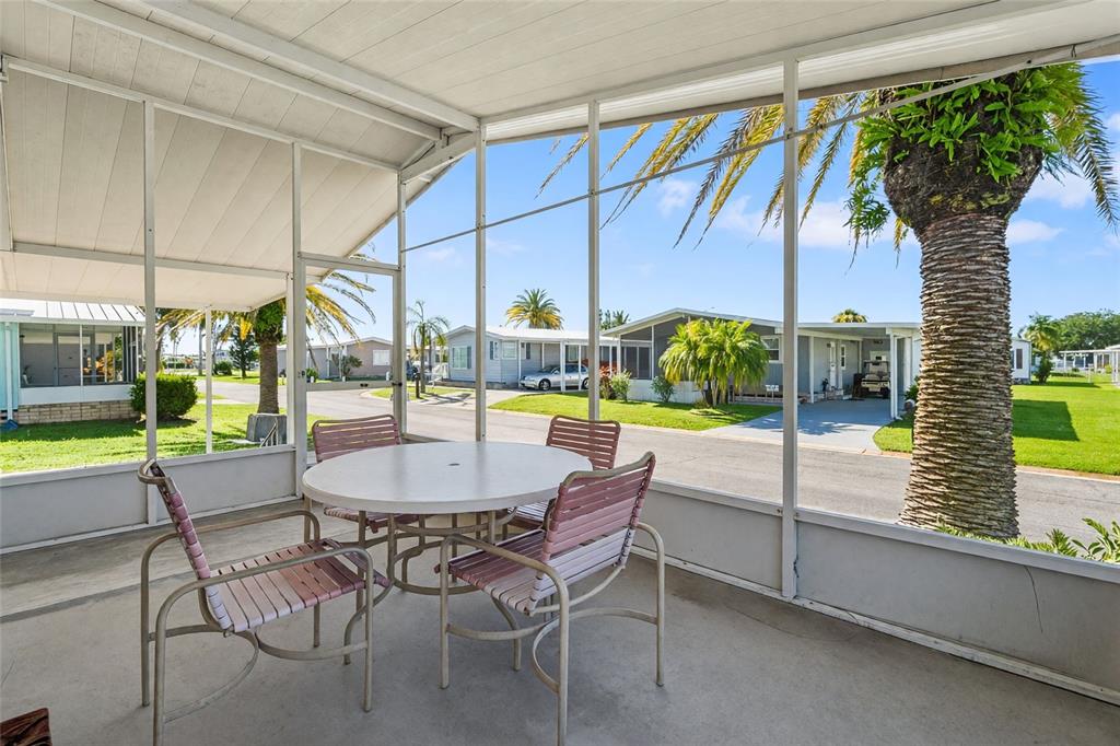 A screened-in patio features a round table with four chairs overlooking a residential street — 693 RIVERVIEW CIRCLE, NORTH PORT, FL