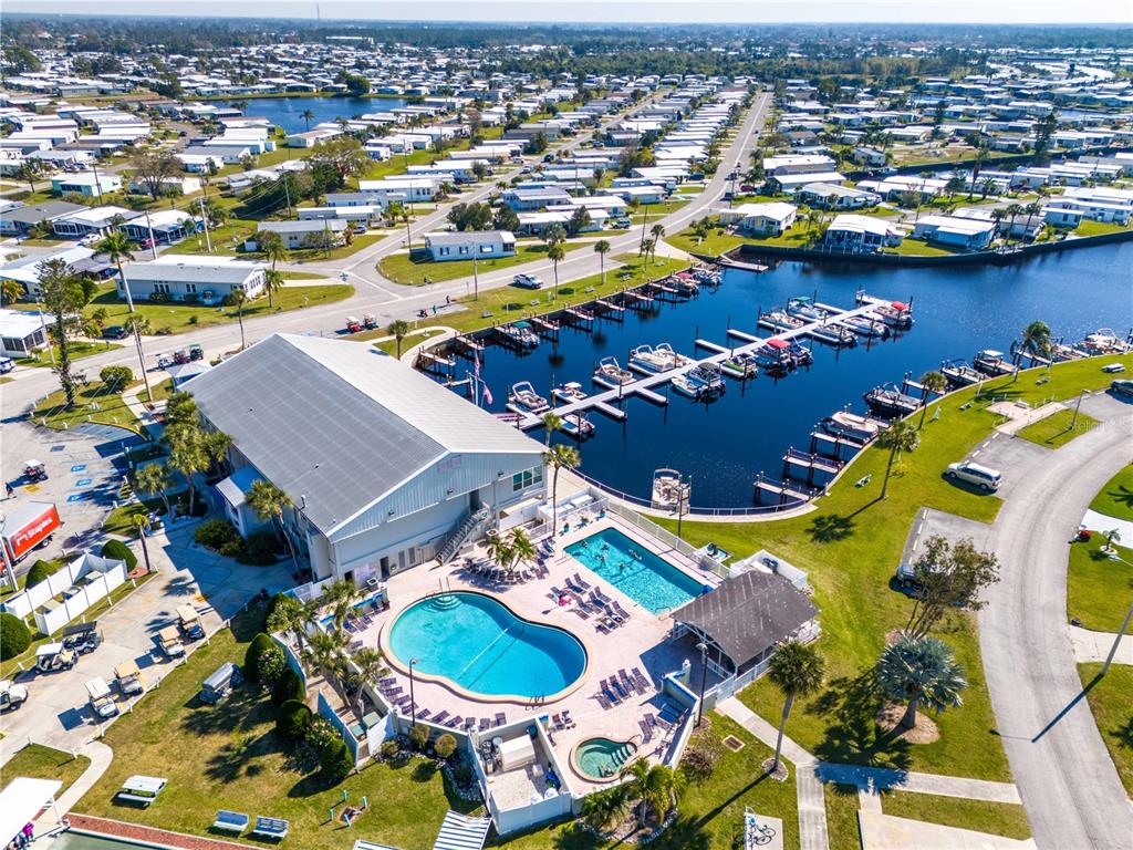 An aerial view shows a community clubhouse with two pools, a hot tub, and a marina — 693 RIVERVIEW CIRCLE, NORTH PORT, FL