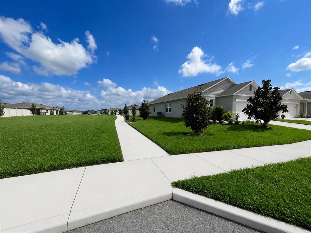 A sidewalk leads past a suburban house with a green lawn under a blue sky — 3648 SUNGROVE CIRCLE, SANFORD, FL