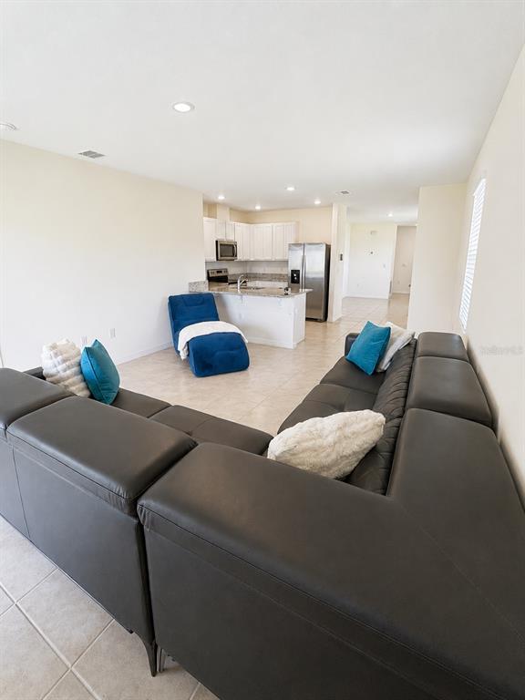 A living room with a large dark sectional sofa faces an open kitchen with white cabinets — 3648 SUNGROVE CIRCLE, SANFORD, FL