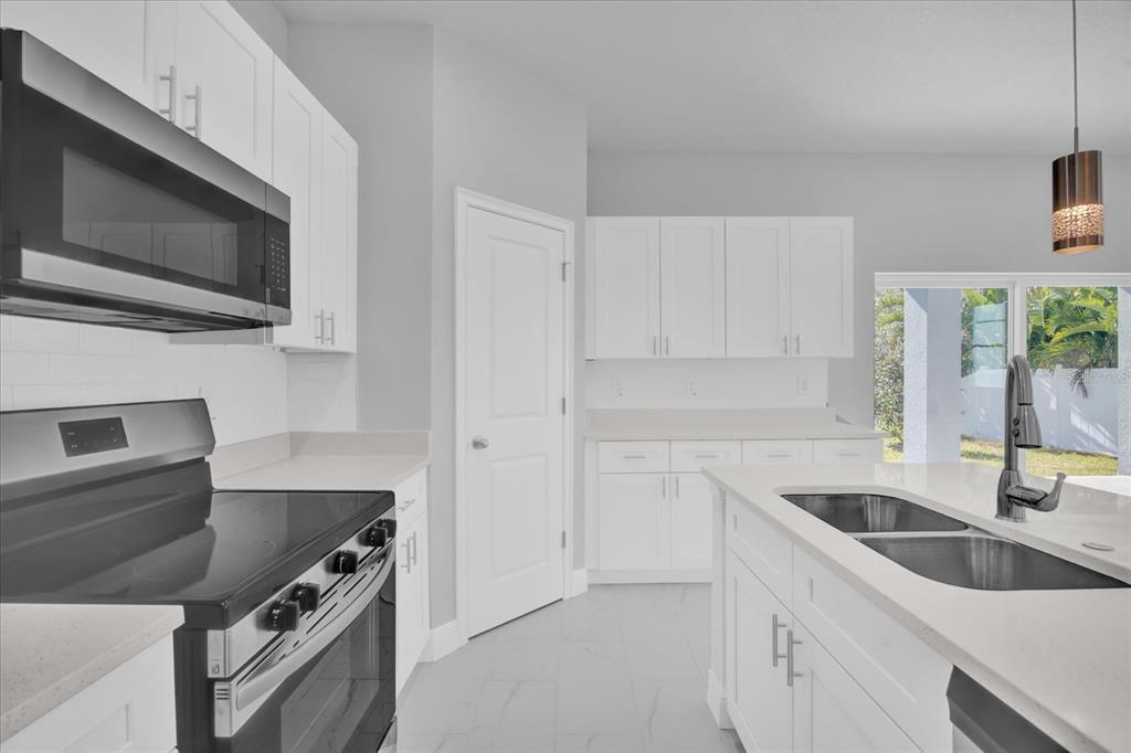 A modern kitchen features white cabinets, stainless steel appliances, a center island, and tile flooring — 1251 ASH TREE COVE, CASSELBERRY, FL