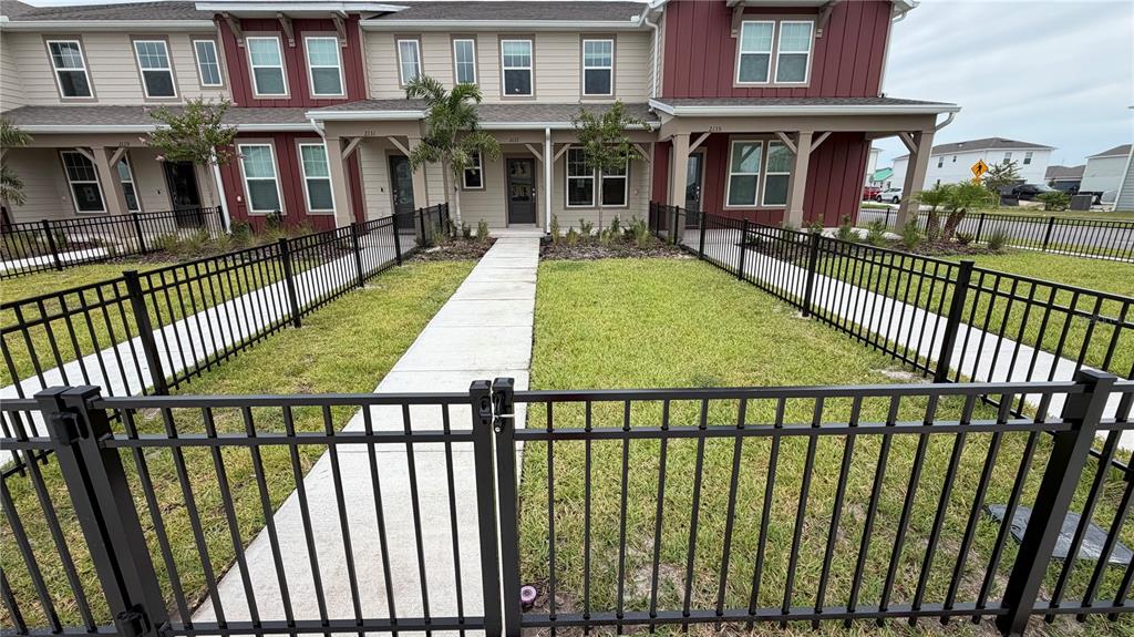 A black metal fence encloses the front yards and walkways of a multi-unit townhouse building — 2133 SOUTHBURY DRIVE, KISSIMMEE, FL