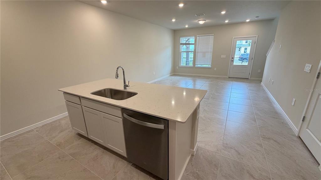 A kitchen island with a sink and dishwasher sits in an open-concept living area — 2133 SOUTHBURY DRIVE, KISSIMMEE, FL