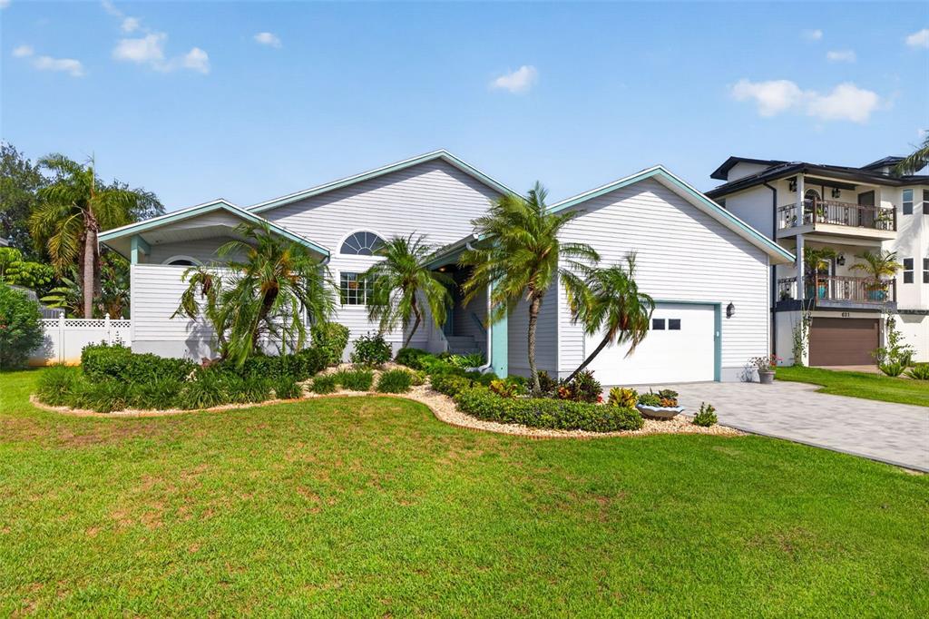 A light-colored, single-story house with a garage, palm trees, and a landscaped front yard — 615 MONTE CRISTO BOULEVARD, TIERRA VERDE, FL