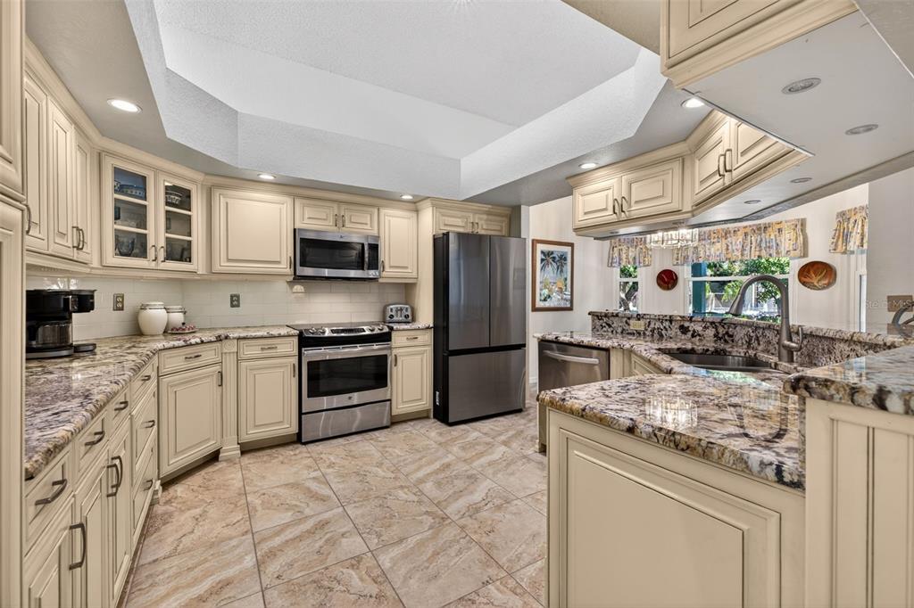 A living room features a vaulted ceiling, light blue walls, a fireplace, and tile flooring — 615 MONTE CRISTO BOULEVARD, TIERRA VERDE, FL