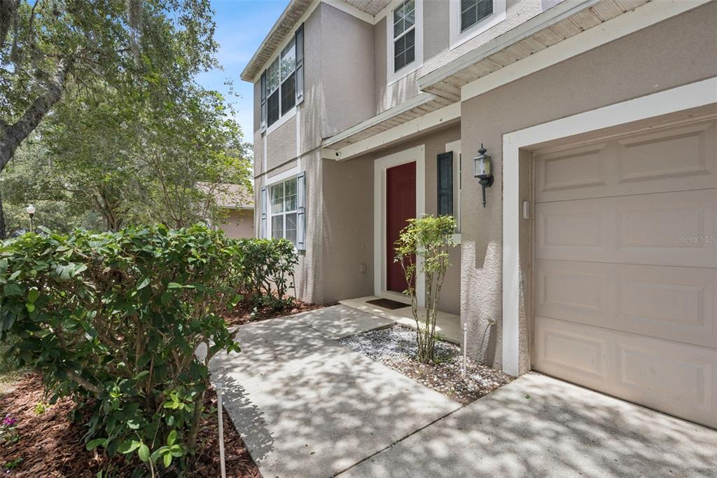 A two-story house exterior features a beige stucco facade, a red front door, and a garage — 381 MISTY OAKS LANE, EUSTIS, FL