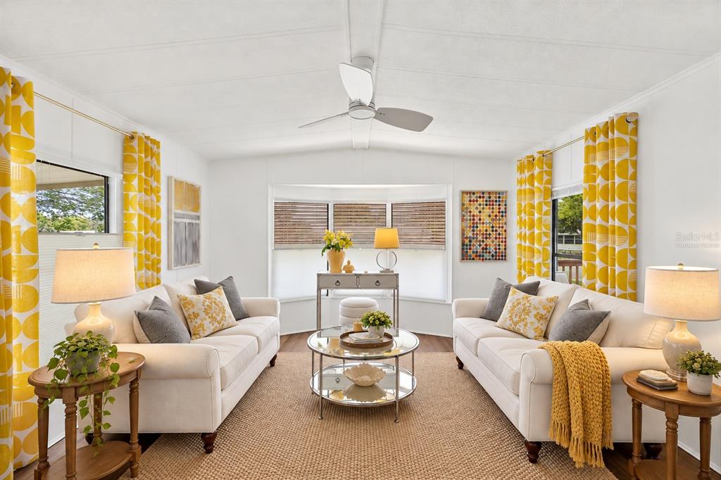 A bright living room features grey armchairs, yellow accent pillows, and a glass coffee table — 727 ROLLING HILLS DRIVE, PORT ORANGE, FL