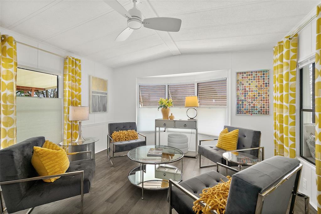 A living room features four dark gray chairs, a round glass table, and yellow patterned curtains — 727 ROLLING HILLS DRIVE, PORT ORANGE, FL