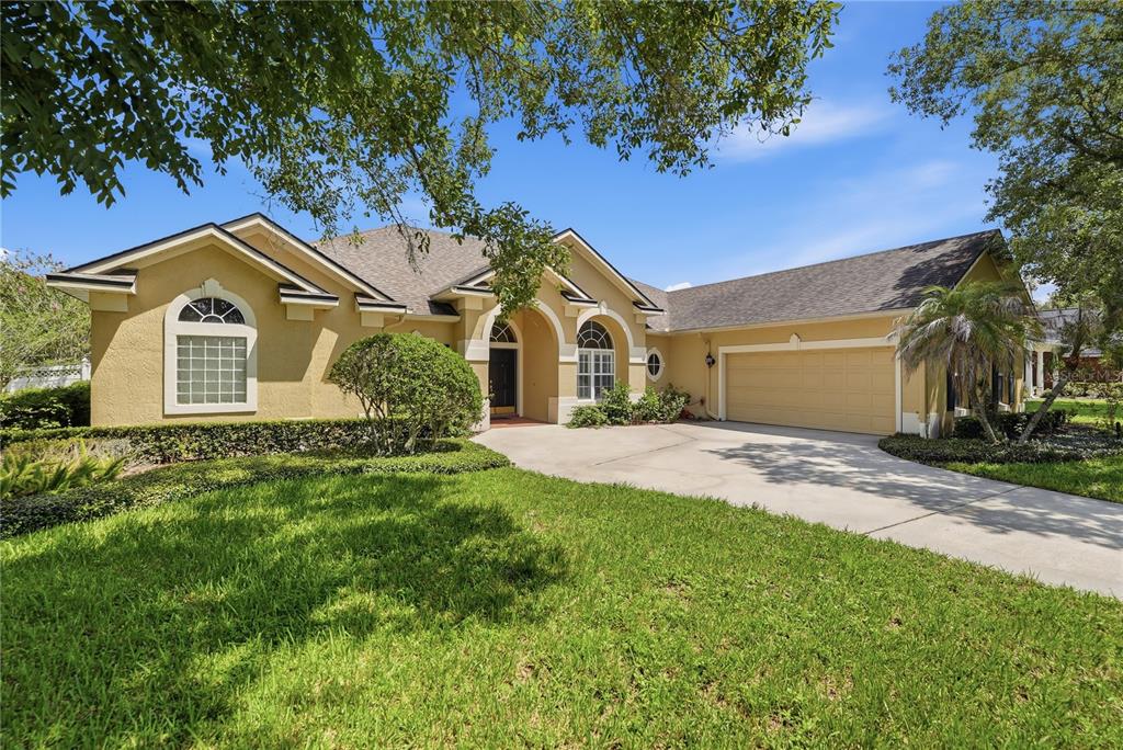 A single-story yellow house with a two-car garage and a concrete driveway — 11457 SWIFT WATER CIRCLE, ORLANDO, FL
