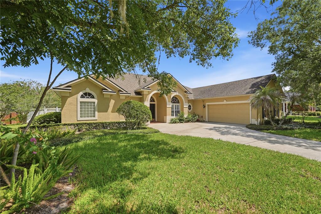 A single-story tan stucco house with a two-car garage and a concrete driveway — 11457 SWIFT WATER CIRCLE, ORLANDO, FL