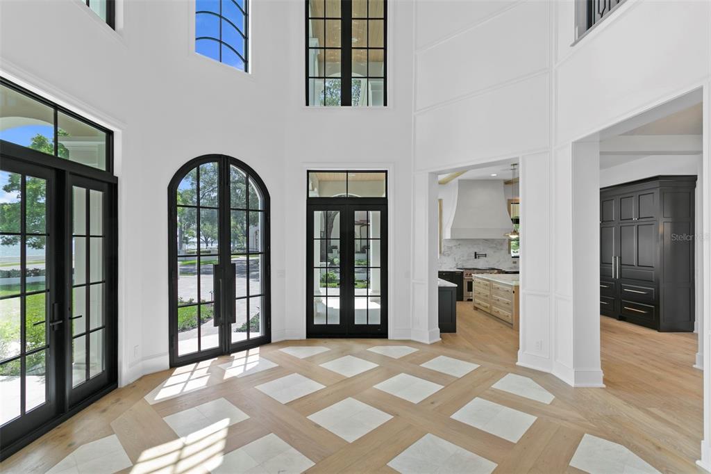 A bright foyer features white walls, black-framed doors, and a patterned wood and stone floor — 3907 BAYSHORE BOULEVARD, TAMPA, FL
