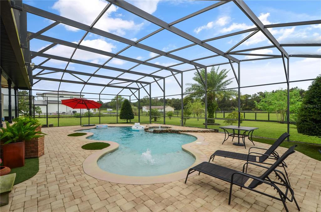 A screened-in patio features a swimming pool with a fountain, lounge chairs, and outdoor furniture — 2393 APPY LANE, APOPKA, FL