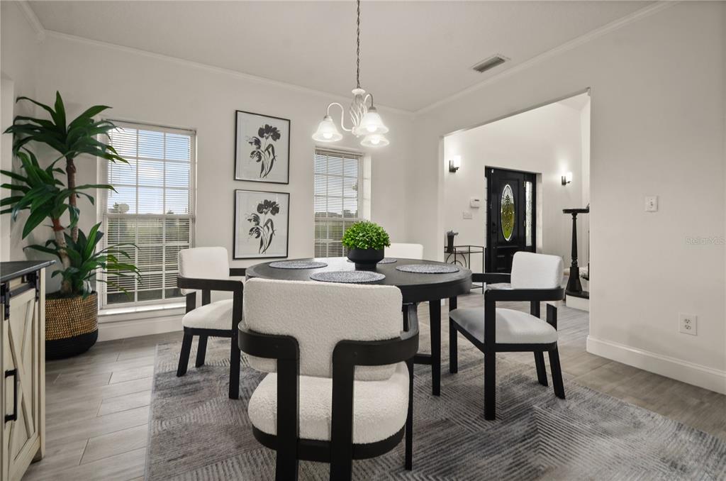 A dining room features a round black table, four upholstered chairs, and a patterned area rug — 2393 APPY LANE, APOPKA, FL
