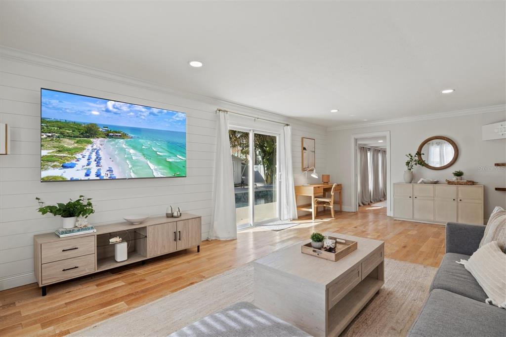 A living room features white shiplap walls, a large wall-mounted television, and light wood flooring — 326 S LIME AVENUE, SARASOTA, FL