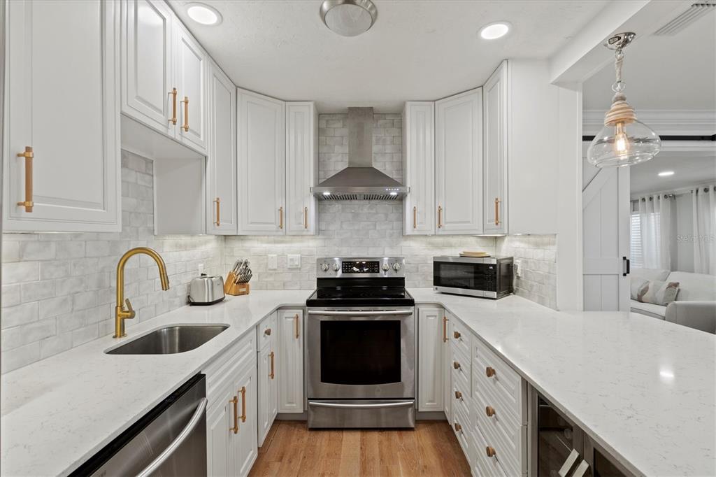 A modern kitchen features white cabinetry, stainless steel appliances, gold hardware, and a subway tile backsplash — 326 S LIME AVENUE, SARASOTA, FL