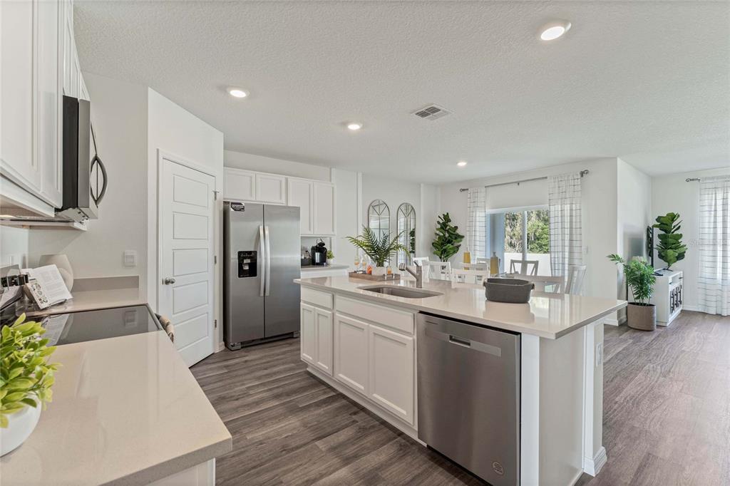 A modern kitchen features white cabinets, stainless steel appliances, a center island, and wood-look flooring — 2759 ADELINE AVENUE, WINTER HAVEN, FL