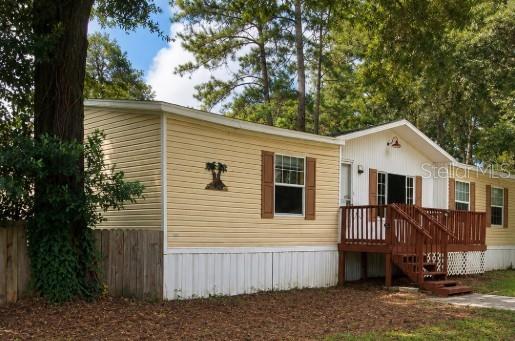 A yellow single-wide mobile home with a wooden front deck sits among trees — 8500 NW 10TH TERRACE, OCALA, FL