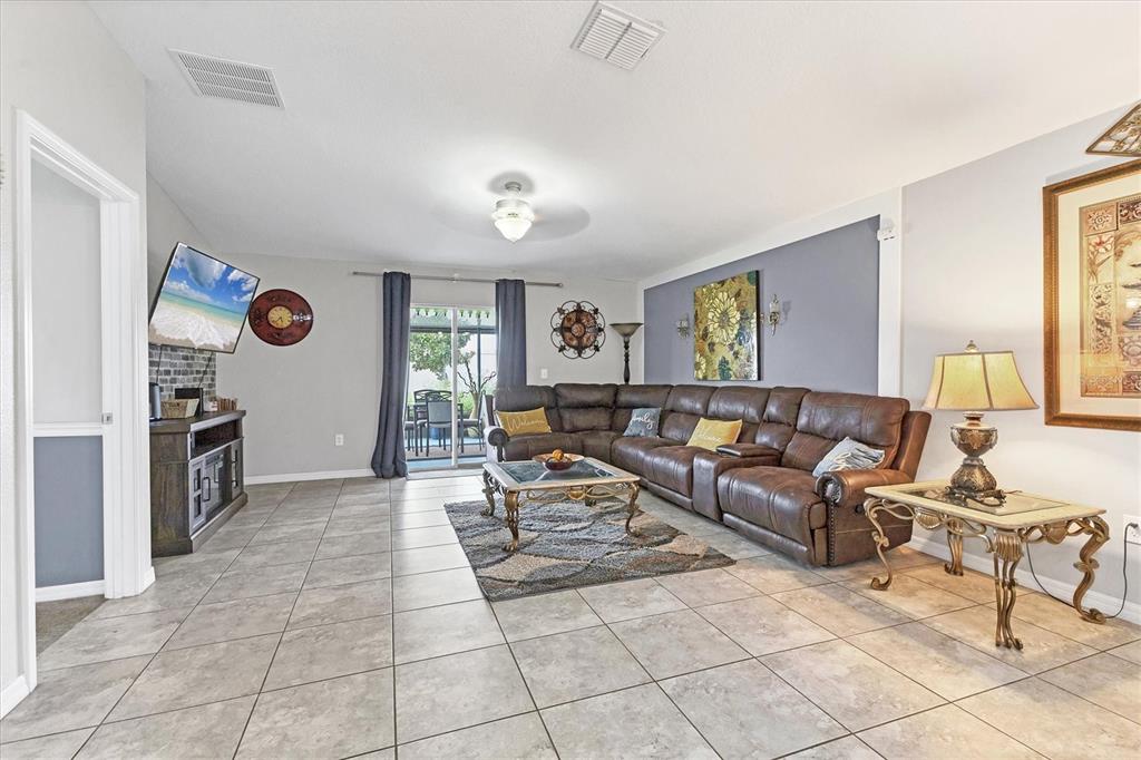 A living room features tile flooring, a brown sectional sofa, and a sliding glass door — 16505 MYRTLE SAND DRIVE, WIMAUMA, FL