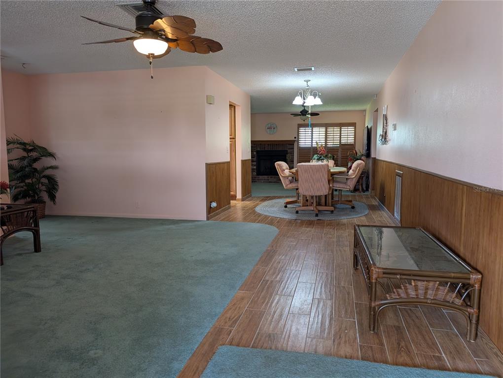 A living and dining area features green carpeting, wood-look tile flooring, and wood wainscoting — 9204 36TH WAY N UNIT 6, PINELLAS PARK, FL